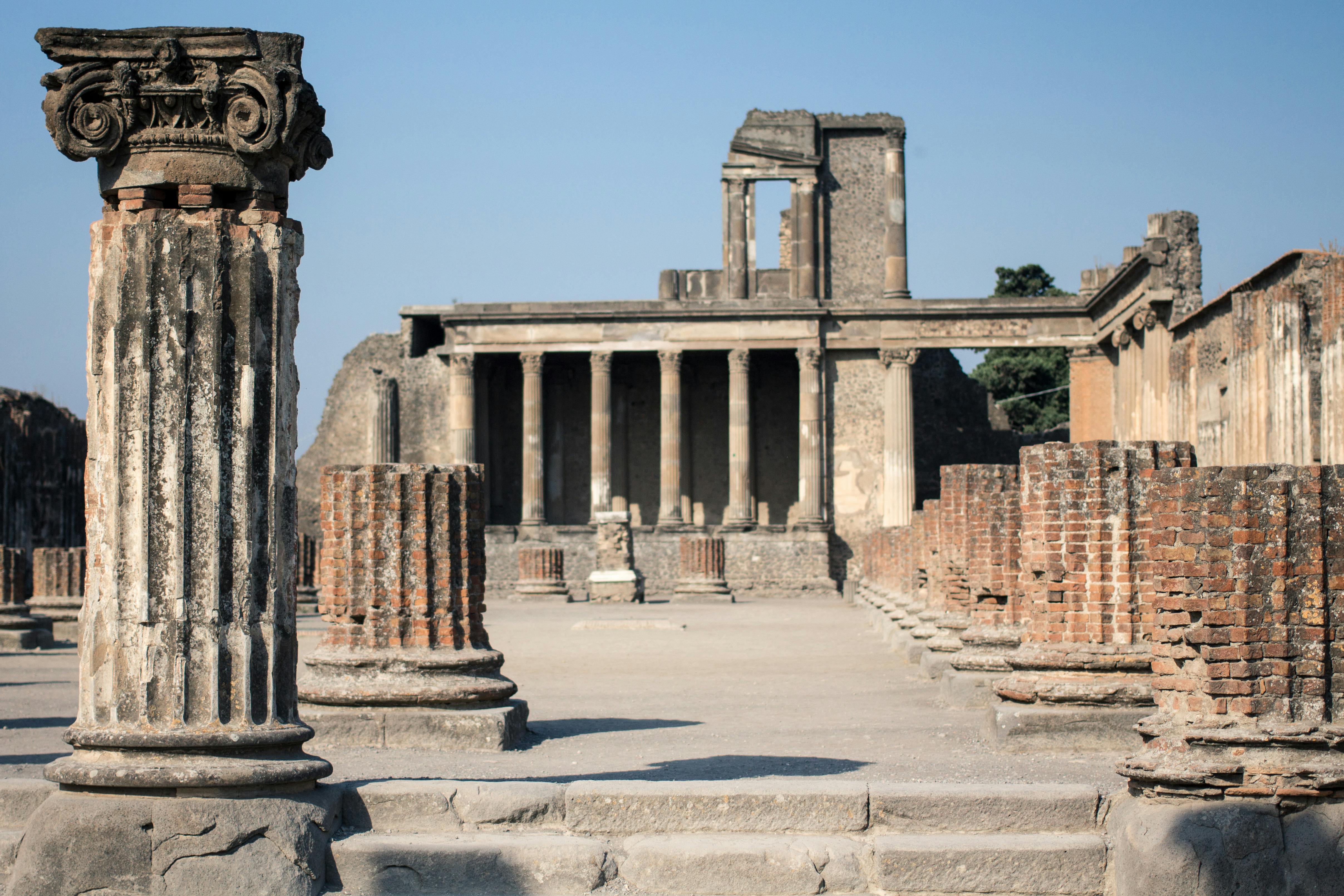 Des ruines anciennes avec des colonnes et une structure partiellement effondrée sous un ciel bleu clair.