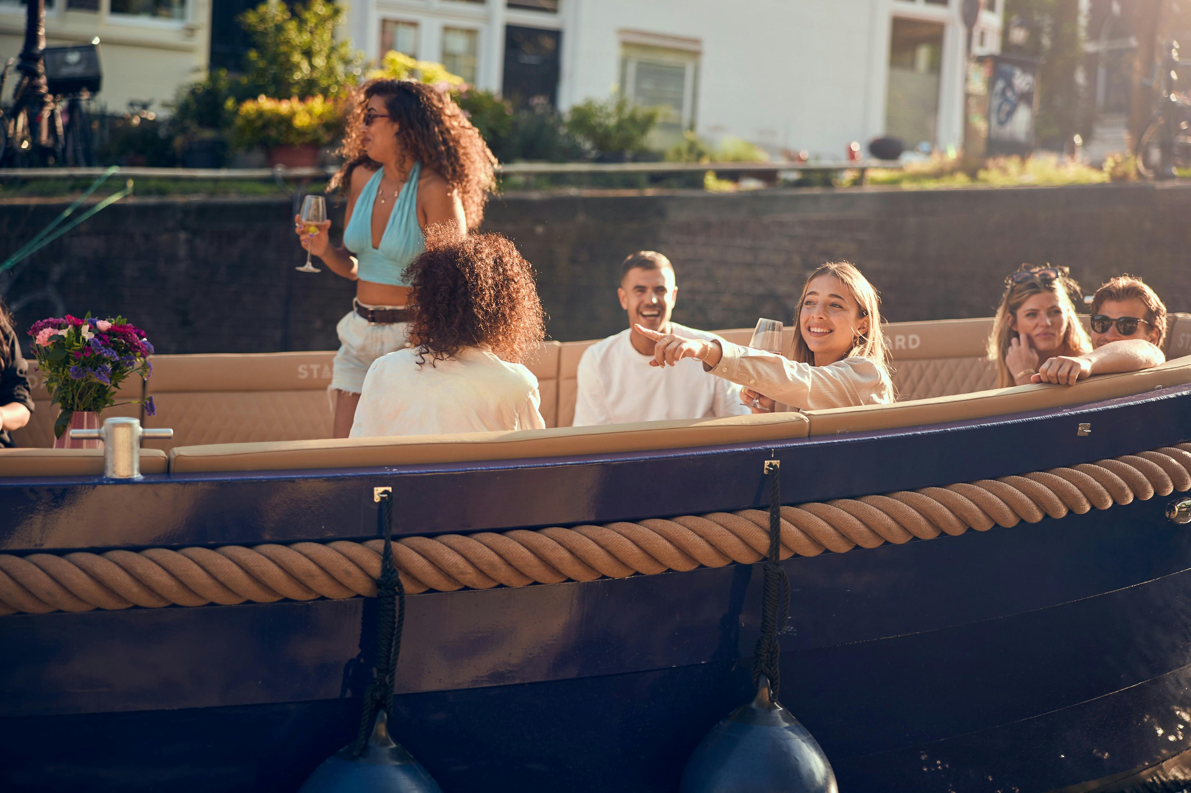 天気のいい日に屋外で、青い外側のロープのディテールが施されたボートに座って笑う人々のグループ。