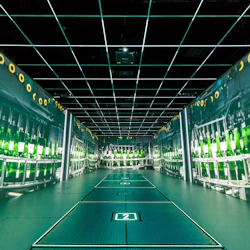 Ett rum med projicerade bilder av gröna flaskor på en monteringslinje, med ett gallerat tak och ett märkt golv märkt "2".