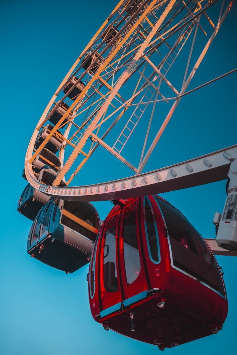 Close-up of a Ferris wheel with red and black gondolas against a clear blue sky.