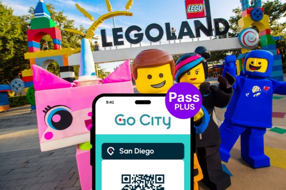 Tre Lego figurer poserar framför en LEGOLAND-skylt, med en Go City Pass Plus för San Diego QR-kod som visas i förgrunden.