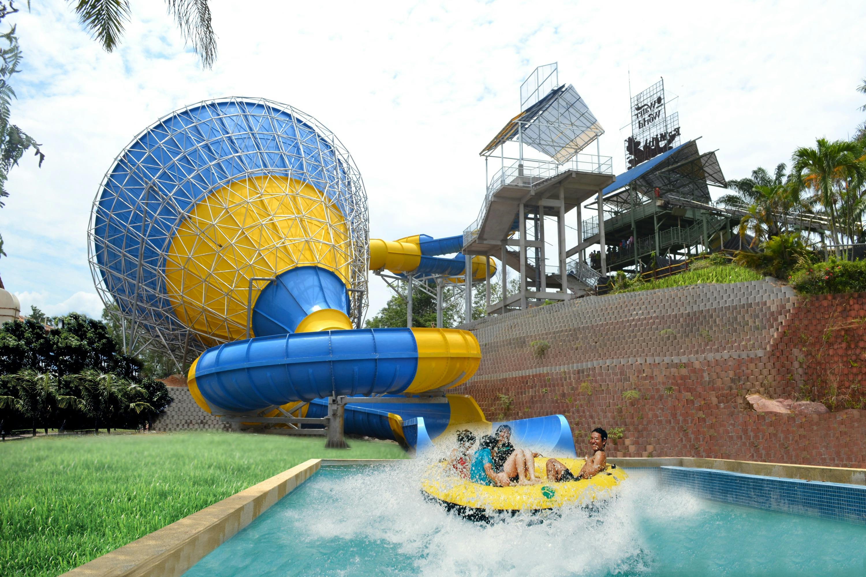 Mensen die genieten van een waterattractie in een geel vlot, terwijl ze uit een blauw-gele waterglijbaan komen in een pretpark.