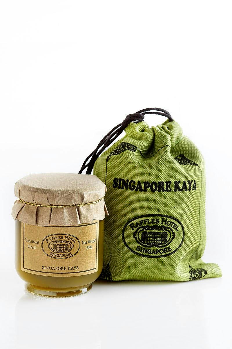 A jar of Singapore Kaya with a beige label and cap, next to a green drawstring bag labeled "Singapore Kaya."