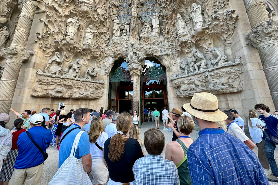 A group of people standing in front of an intricately carved architectural entrance with statues and details.