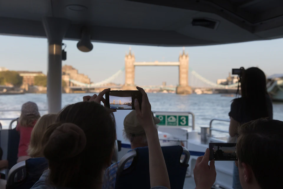 People on a boat taking photos of Tower Bridge in London during daylight.
