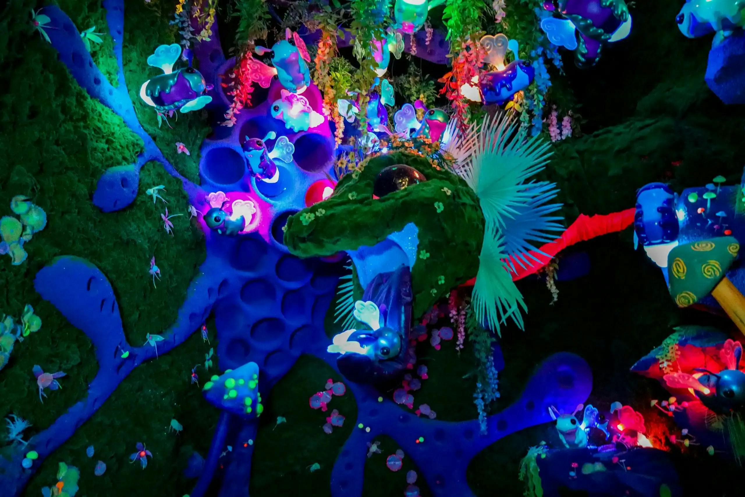 Colorful, vibrant scene with glowing, futuristic plants and animals, including a giant green fish head and butterflies in a fantasy environment.