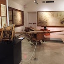 Room filled with wooden mechanical models and large sepia drawings on walls, separated by a white rope barrier.