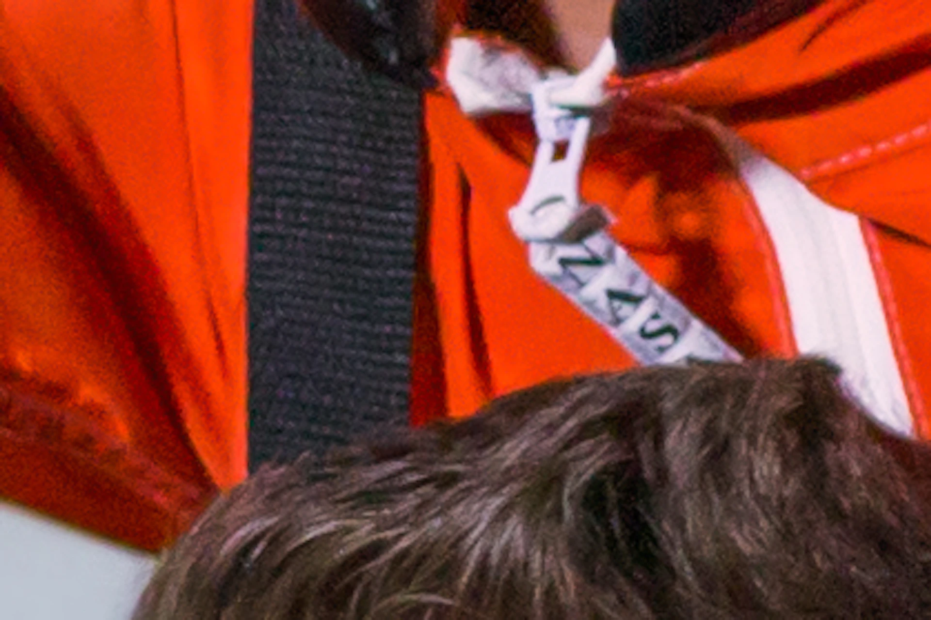 A child in an orange suit sits on a man’s shoulders, both smiling and pointing, with an image of Earth from space in the background.