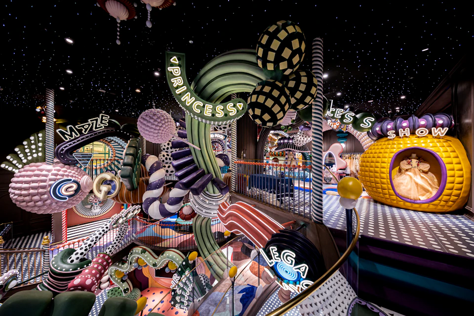 A colorful, whimsical indoor playground with abstract shapes, vibrant colors, and a starry ceiling.