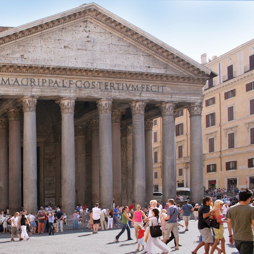 I visitatori si radunano davanti al Pantheon di Roma, in Italia, con le sue grandiose colonne e l'architettura antica sotto un cielo limpido.