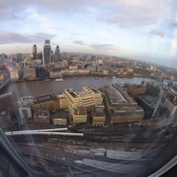 Flygfoto över Londons skyline med skyskrapor, Themsen och stadsbyggnader sedd genom ett glashölje.
