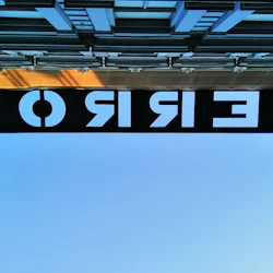 En byggnadsfasad med en svart skylt som visar ordet "TERROR" med vita bokstäver, fotograferad underifrån mot en klar himmel.