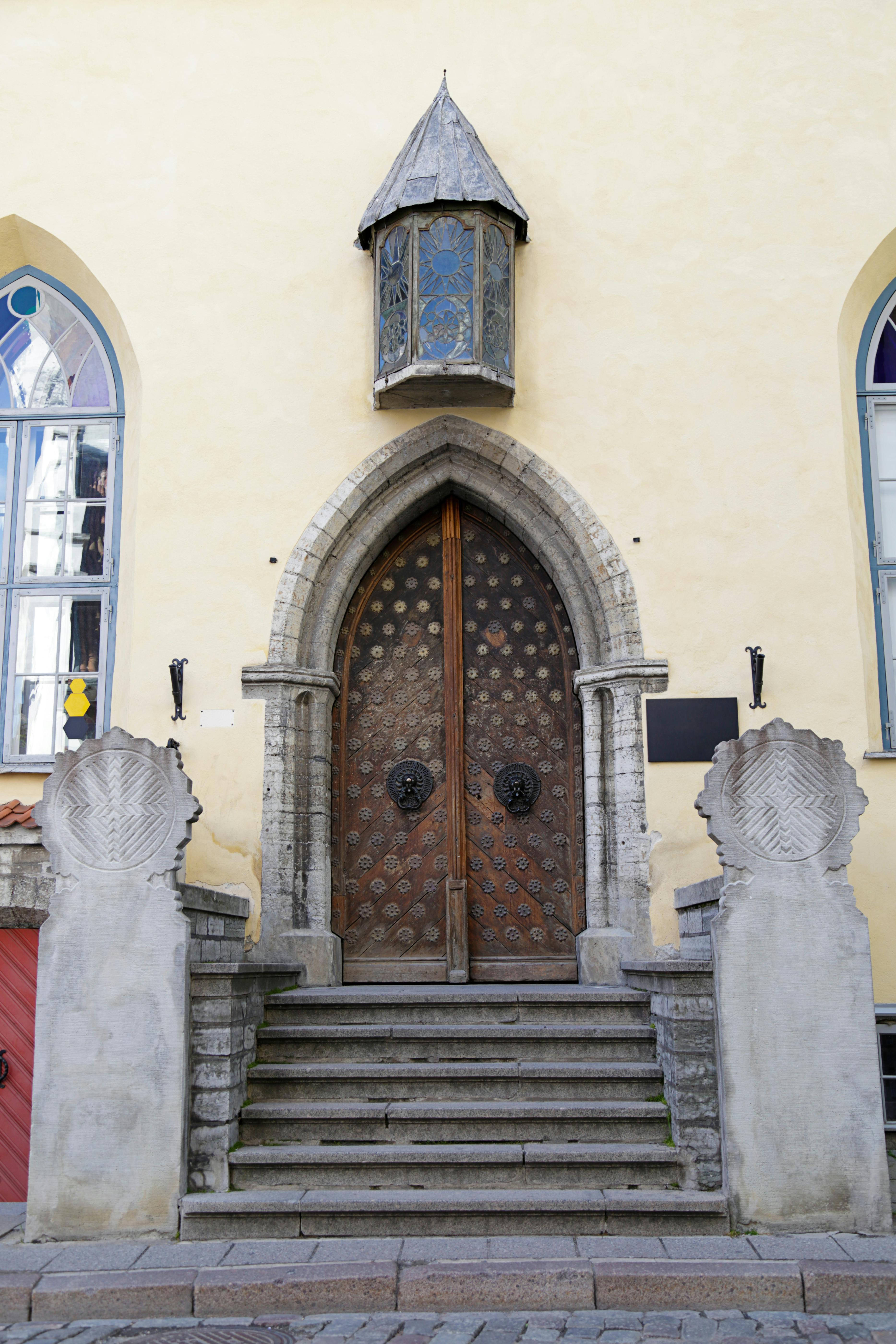 Ornate wooden double doors with stone archway, flanked by two spiral stone columns, and a decorative window above.