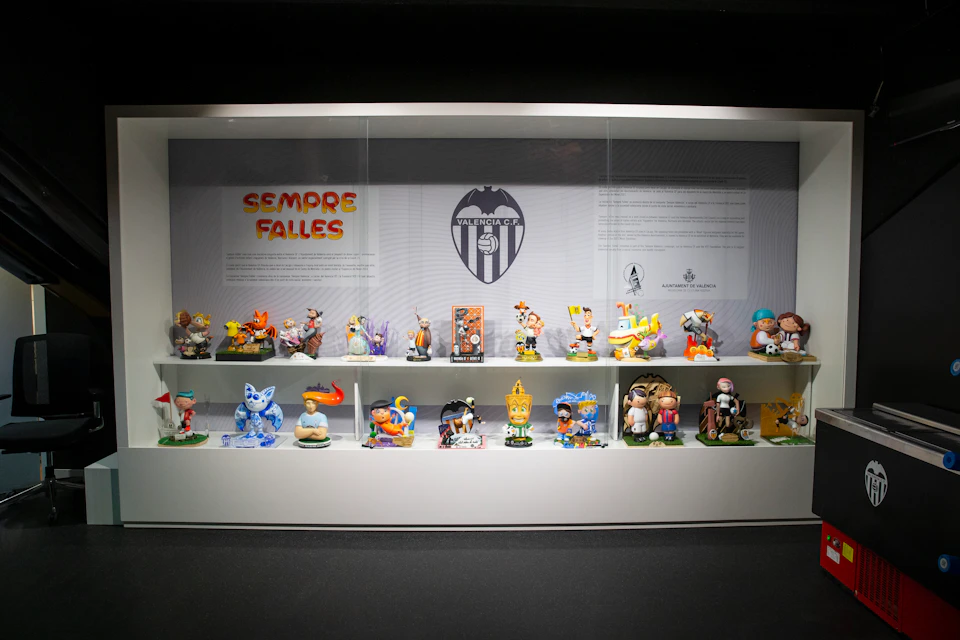 A display case with various colorful figurines, a Valencia CF logo, and text "Sempre Falles" set against a white background.
