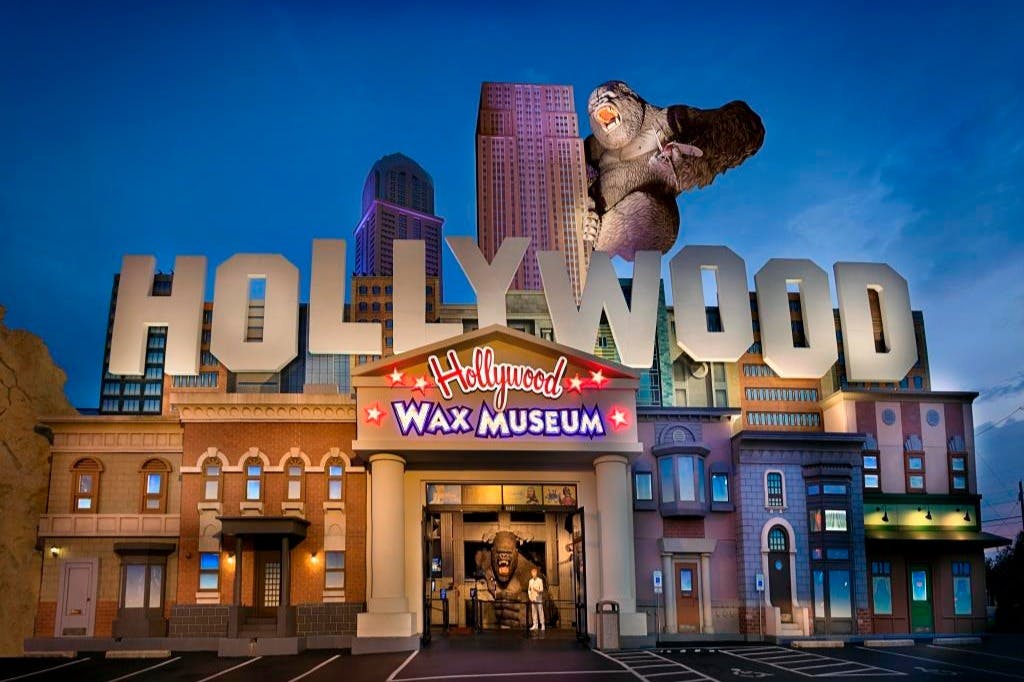 La façade du Hollywood Wax Museum, sur le toit de laquelle trône une statue géante de gorille, entourée de bâtiments et d'un ciel radieux.