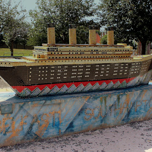 En mosaikstaty på en blå piedestal med orden "Belfast" och "Southampton", omgiven av träd och en park i bakgrunden.