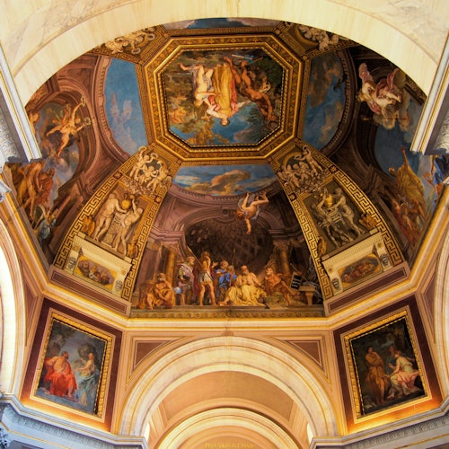 Un soffitto dettagliato e decorato con dipinti che raffigurano varie scene e figure mitologiche, incorniciato da un'architettura classica.