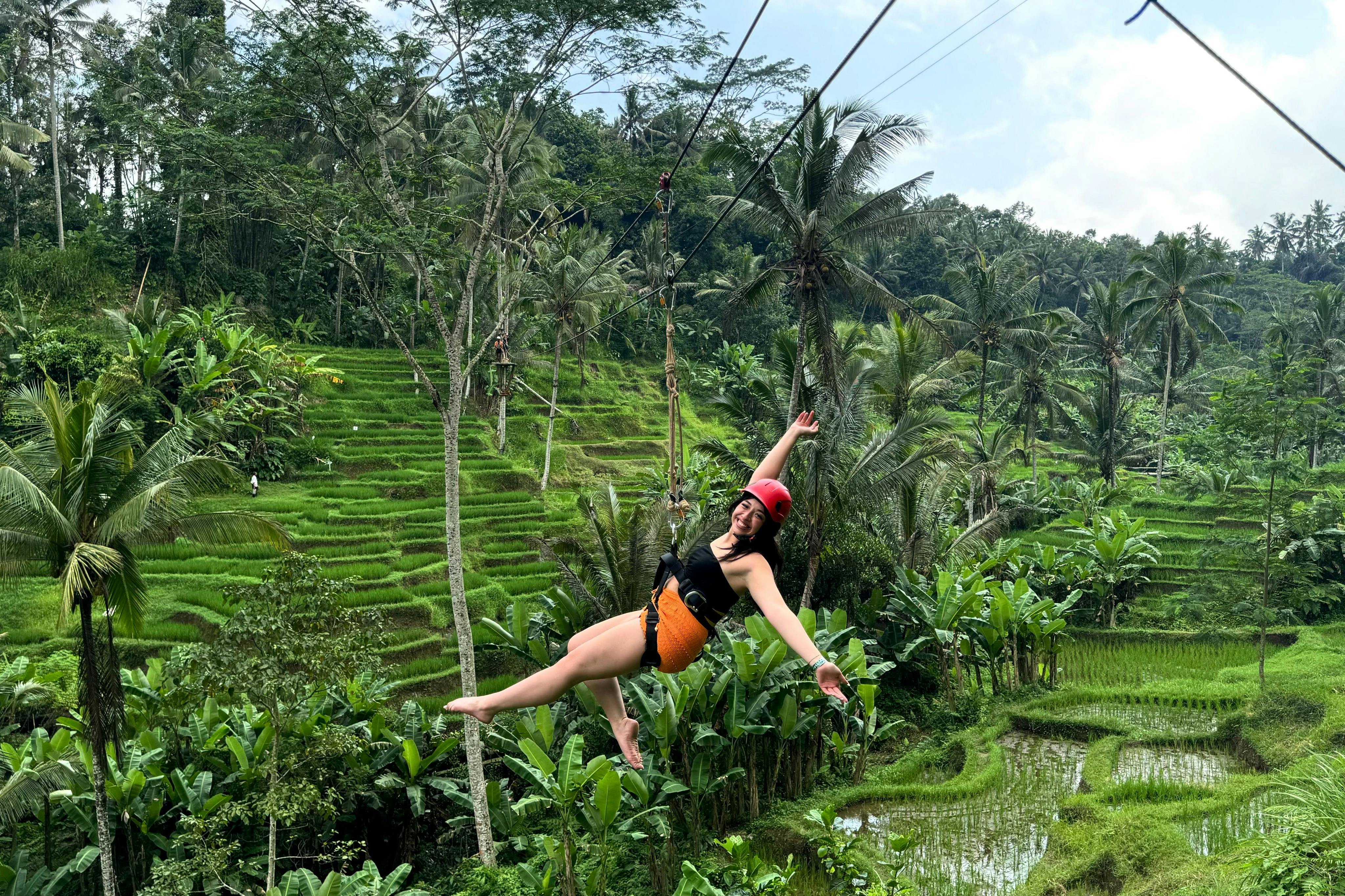 Uファン・フィールド・パークの美しい緑の棚田の上でジップラインを楽しむ女性