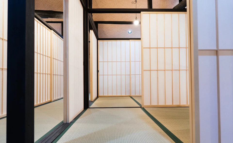 A traditional Japanese-style room with tatami flooring and sliding shoji doors, illuminated by soft indoor lighting.