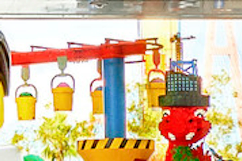 Entrance to LEGOLAND Japan with visitors walking and posing near LEGO character statues under a colorful arch.