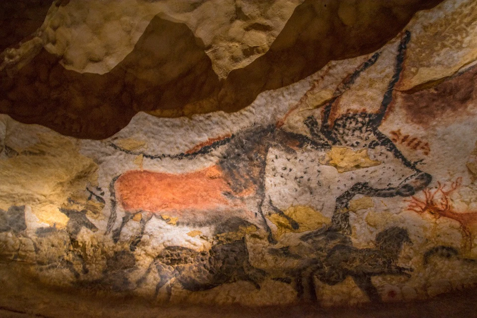 Ancient cave painting depicting animals, including a red and black horse figure, on a textured stone wall.