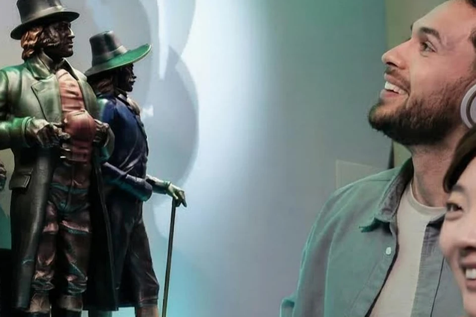 Two people observe historical figurines in a display titled 'The Battle for Beer Domination: A Historical Saga of Competing Tastes.'