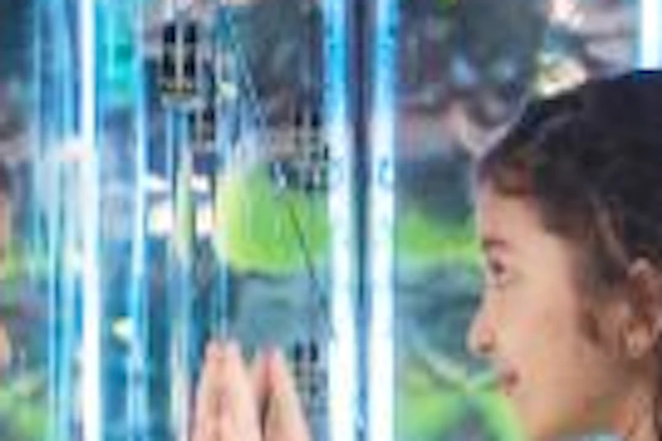 A girl in a yellow skirt looks into a mirror in a room filled with large glowing spheres, with another girl nearby.