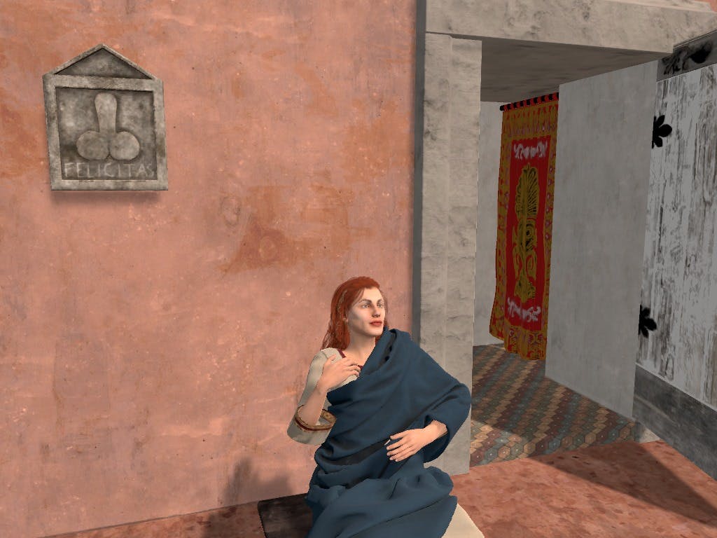 一个长着红色长发的人，披着蓝色织物，坐在门口附近的纹理墙上，里面有五颜六色的窗帘。