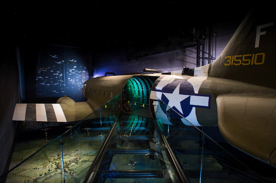 An exhibit showing the interior of a military aircraft, featuring Second World War-era markings, an illuminated walkway and a wall display of small aircraft models.