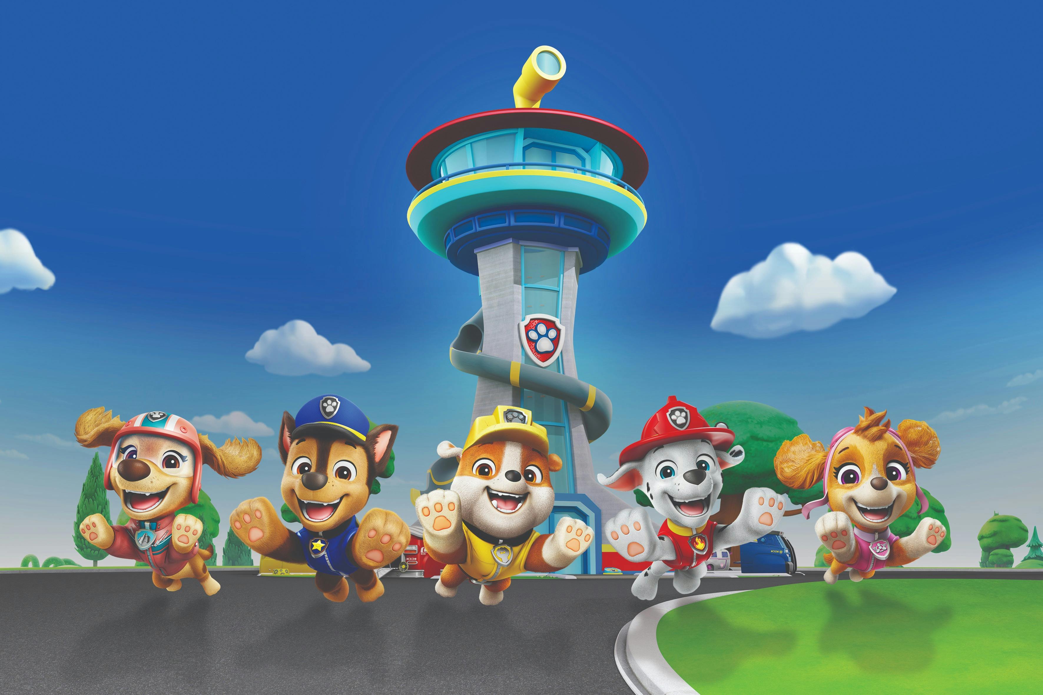 Fem animerade hundar i färgglada kläder hoppar glatt framför ett stiliserat torn under en klarblå himmel med moln.