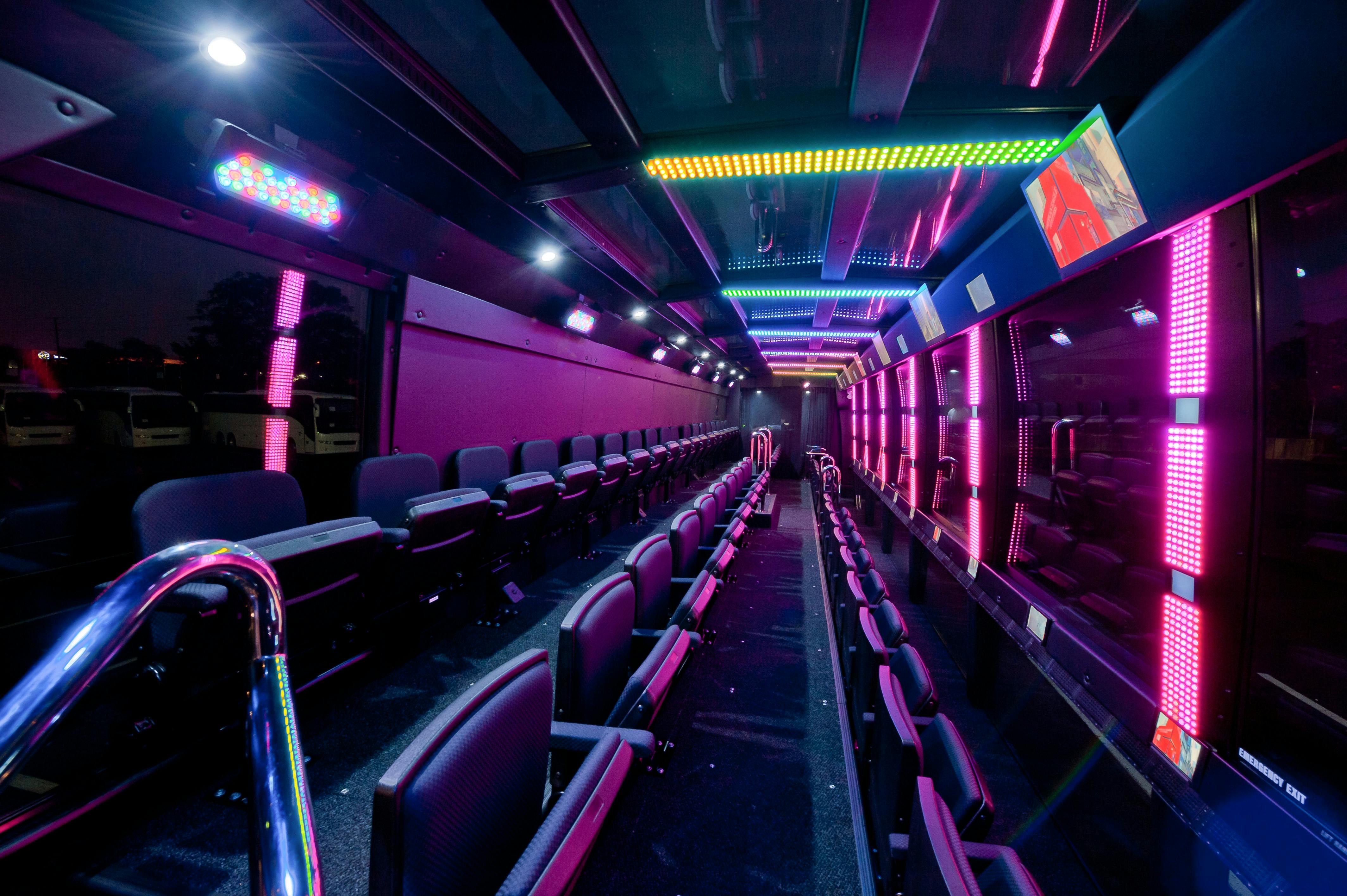 Εσωτερικό λεωφορείου με σειρές κενών καθισμάτων που φωτίζονται από πολύχρωμα φώτα LED στην οροφή και τους τοίχους.