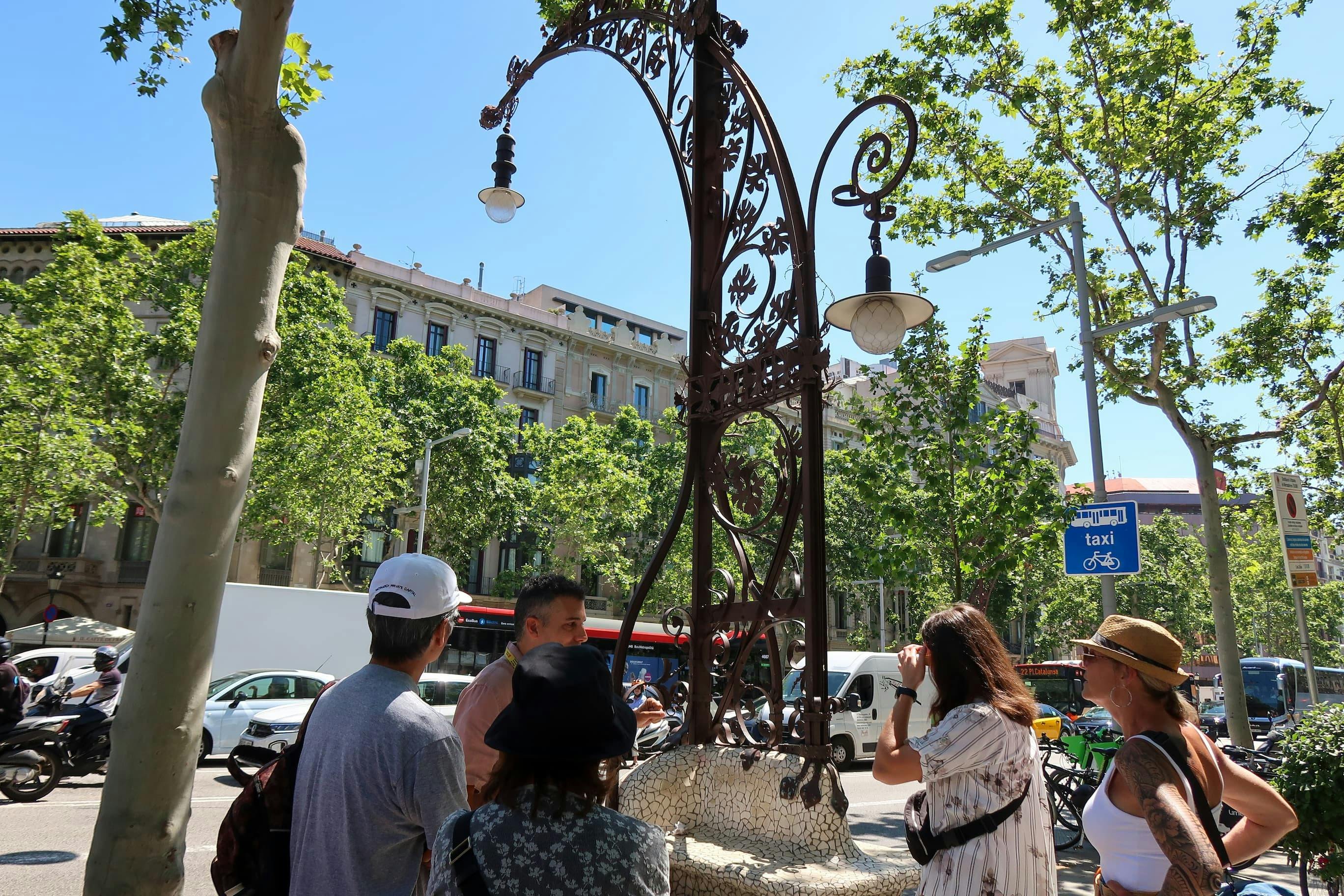 Un petit groupe se rassemble autour d'un lampadaire décoratif de style Gaudi dans le quartier de l'Eixample.