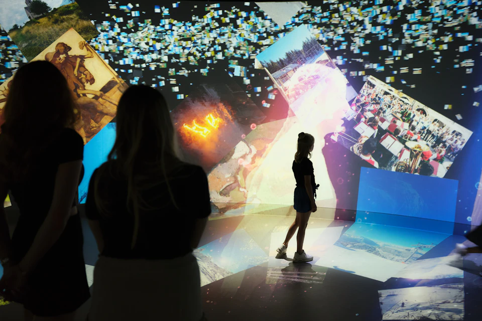 Silhouettes of people observing a colorful digital art display with various images and abstract visuals projected on walls.
