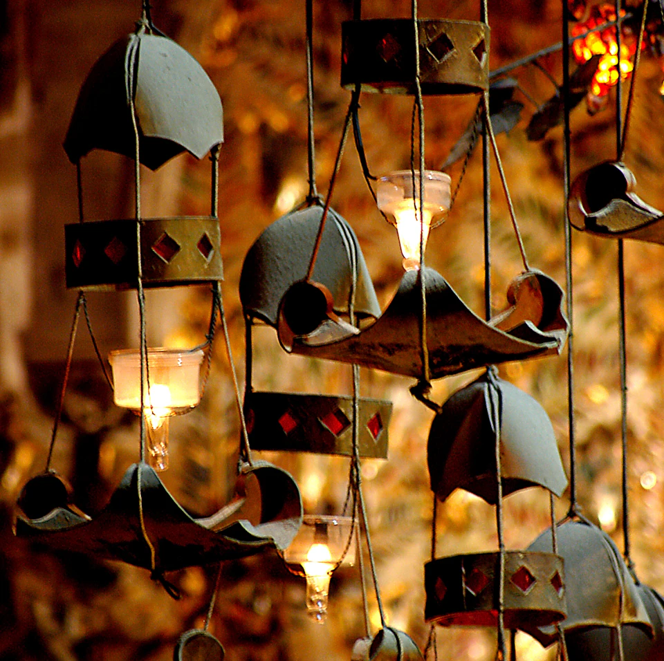 Hanging decorations with bell shapes, small lights, and red diamond patterns, set against a blurred, warm-toned background.