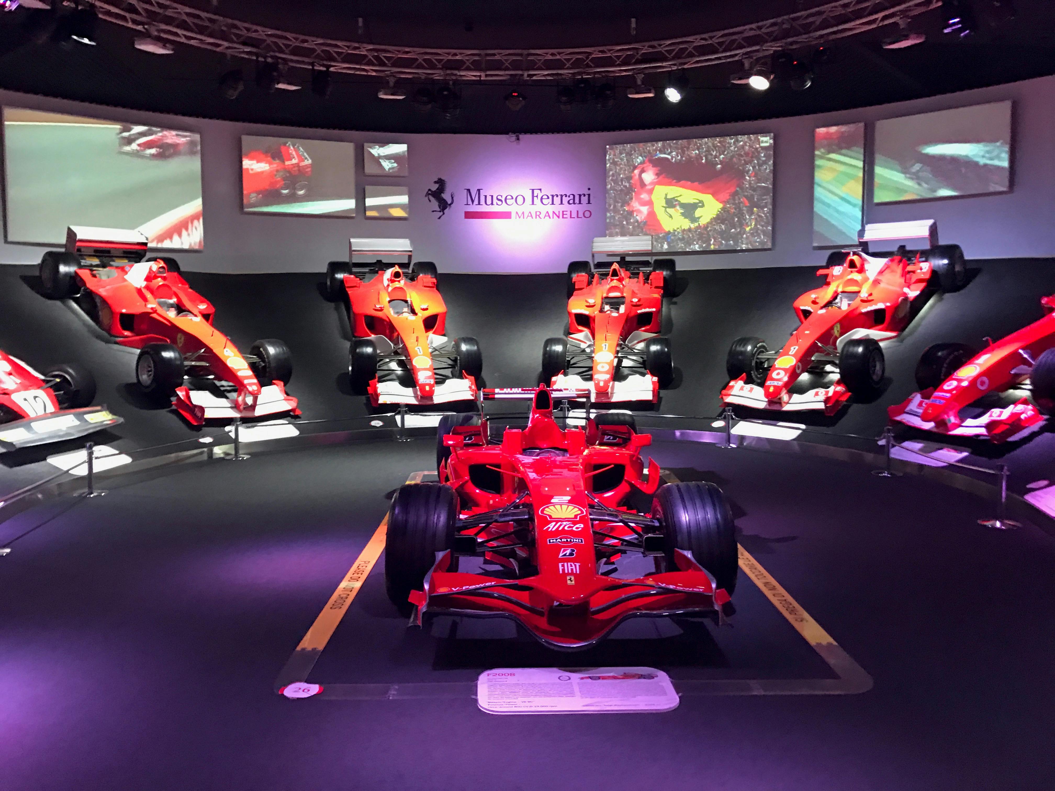 法拉利马拉内罗博物馆展示了红色法拉利一级方程式赛车，并在高架平台上展示了几款车型。