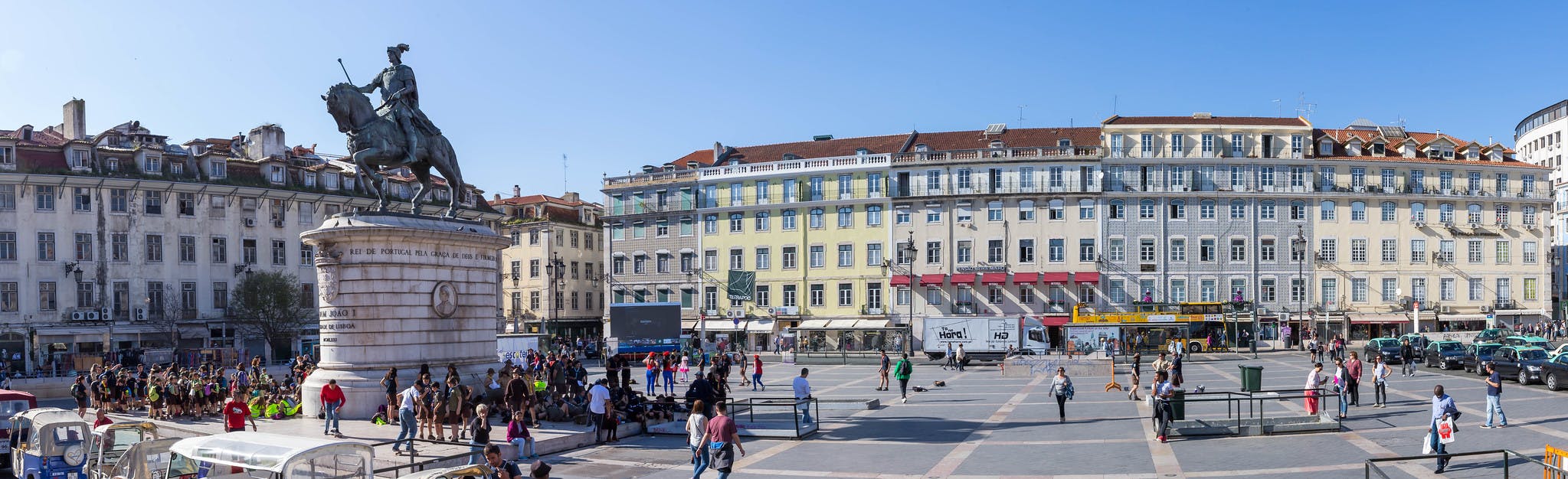 A large square with people gathered around a statue of a man on a horse, surrounded by historic buildings.