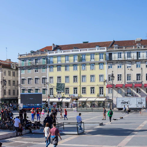 Ett stort torg med människor samlade runt en staty av en man på en häst, omgiven av historiska byggnader.