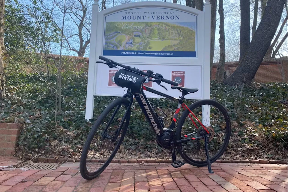 A black Cannondale bicycle parked on a brick path in front of a Mount Vernon welcome sign and trees in the background.