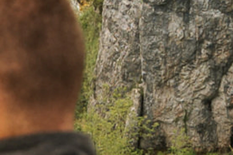 A group of people standing on a wooden balcony overlooking a scenic view of waterfalls and lush greenery.
