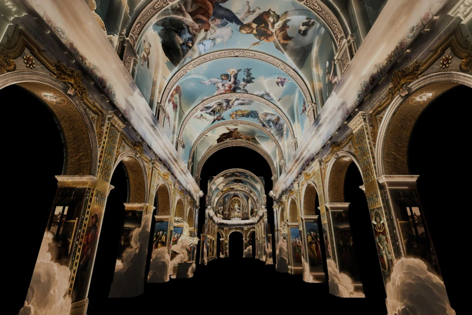 A grand hall with ornate painted ceilings depicting scenes of angels and figures, surrounded by arches and detailed architecture.