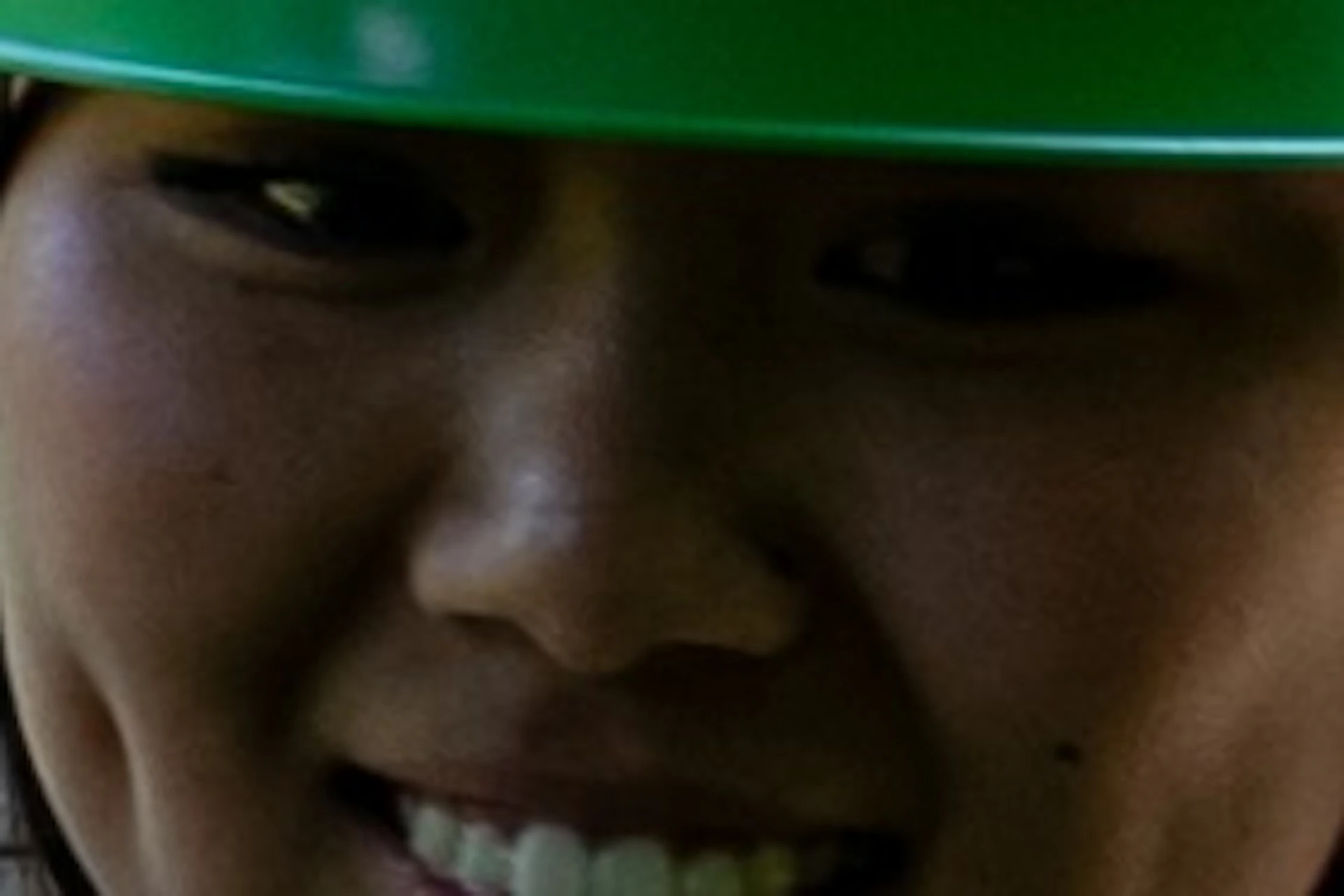 A person wearing a green helmet and safety harness navigates a ropes course in a forested area on a sunny day.