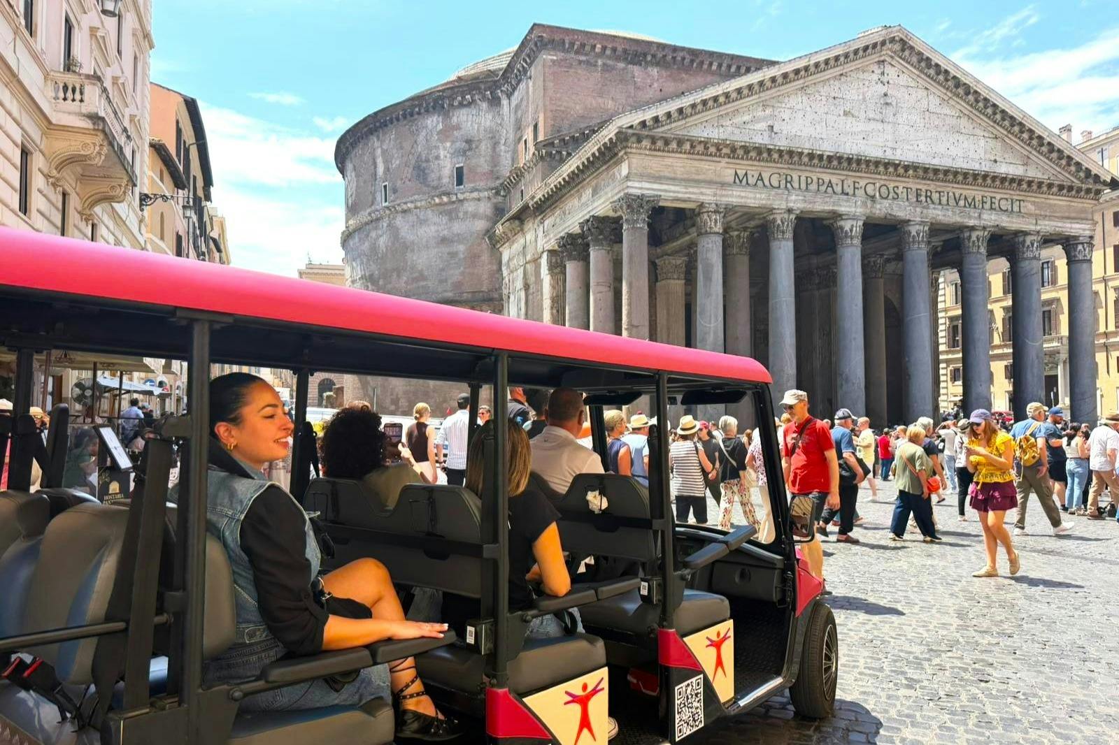 A woman smiles while seated in an open-top tour vehicle in front of the Pantheon in Rome, with tourists walking nearby.