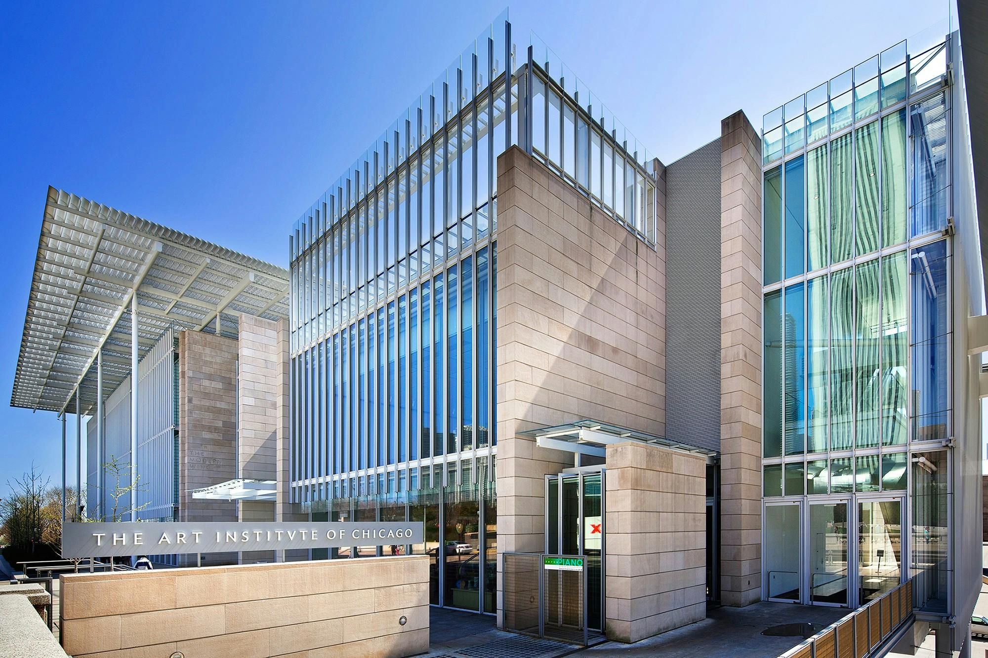 现代化的玻璃和石头建筑立面，晴朗的蓝天下有指示「芝加哥艺术博物馆」的标牌。