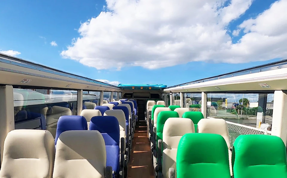The interior of a bus with colorful seats and a clear view of the outside through large windows under a blue sky.