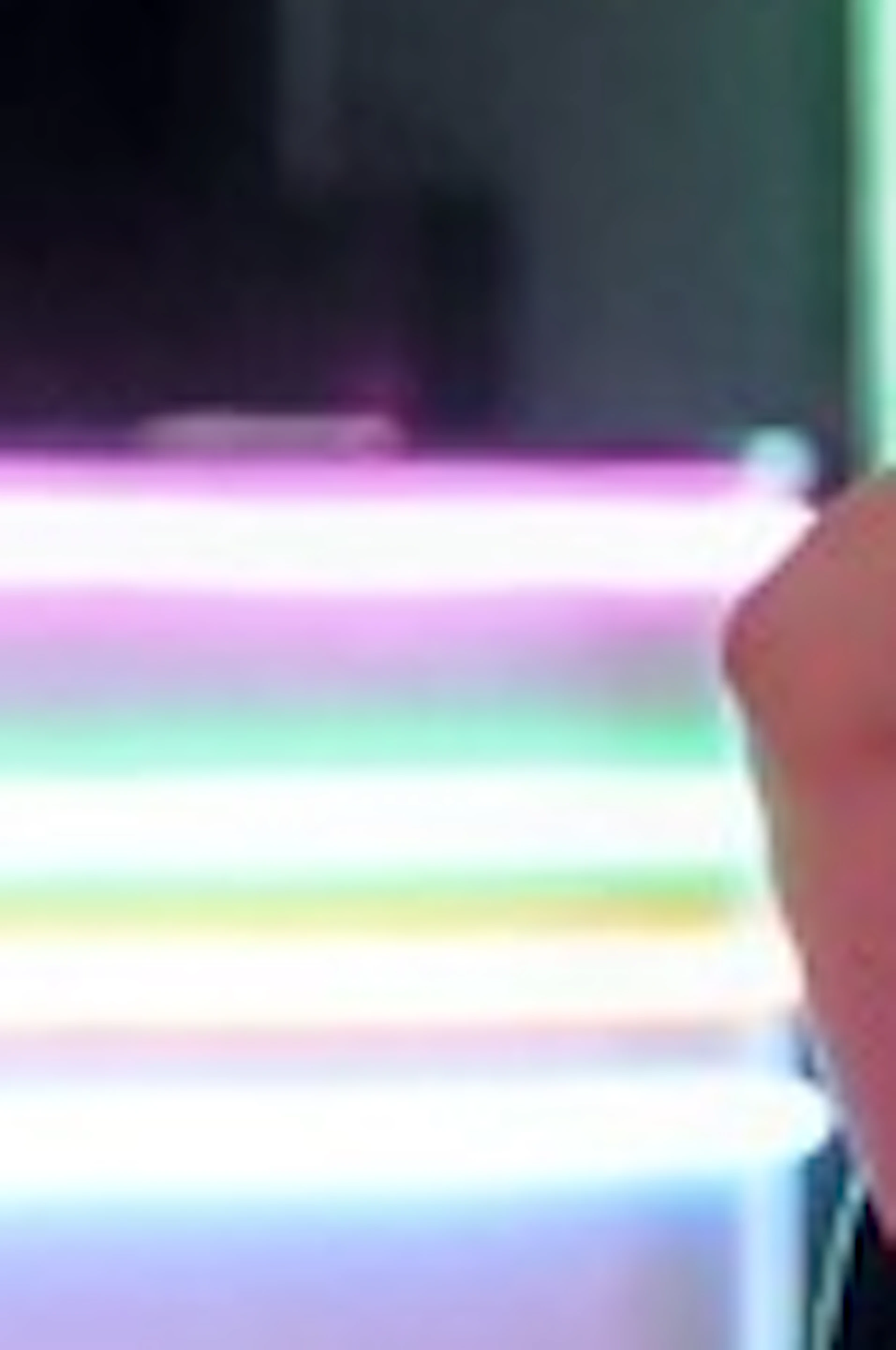 Four people posing playfully in a neon-lit indoor setting with colorful lights and reflective flooring.