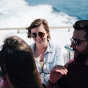 Tre persone che si godono un giro in barca: due di loro sorridono e indossano occhiali da sole. L'oceano è visibile sullo sfondo.