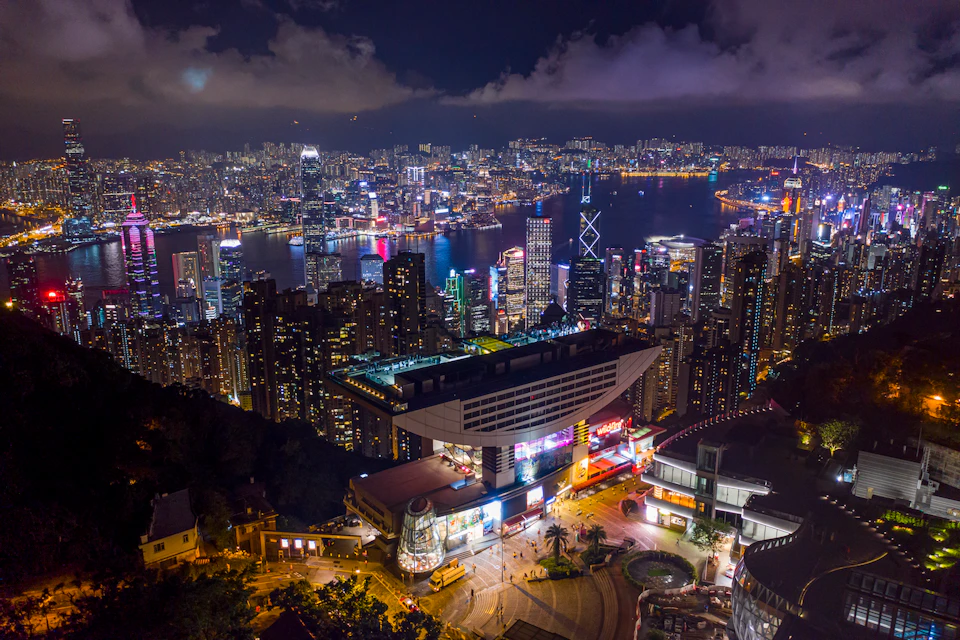 A nighttime cityscape showing a vibrant, illuminated skyline and a modern building in the foreground.