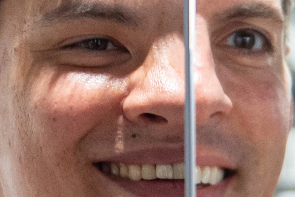 A person in a red shirt is looking into a mirror, with their reflection visible. Geometric designs are in the background.