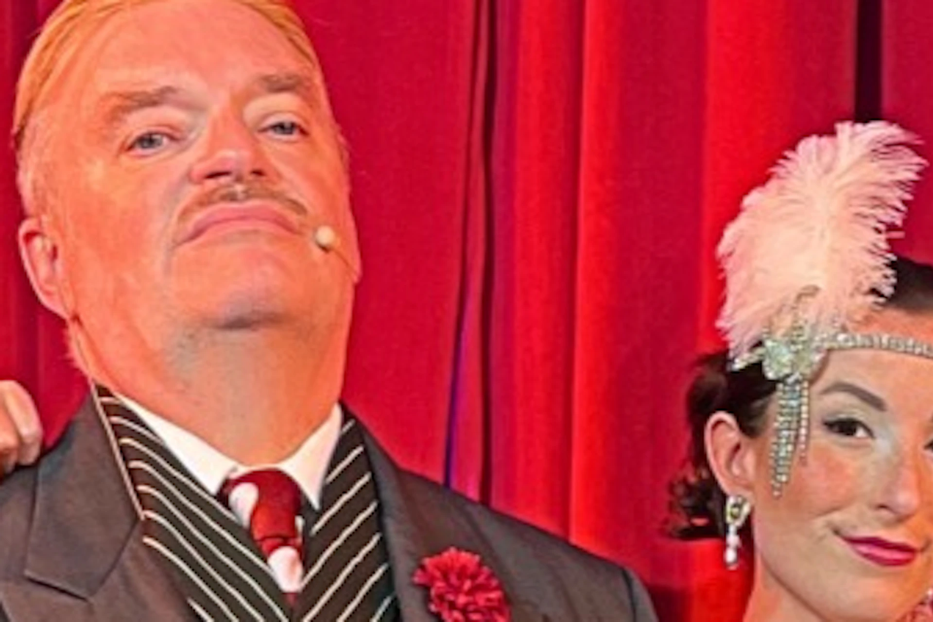 A group of five people dressed in 1920s-style costumes posing in front of a red curtain.