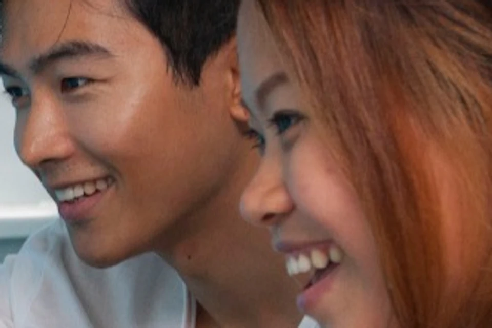 Two people smiling and pointing at underwater scenery through windows in an aquarium tunnel or underwater observatory.